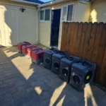 A row of low-grain refrigerant dehumidifiers staged on a driveway before a water damage job
