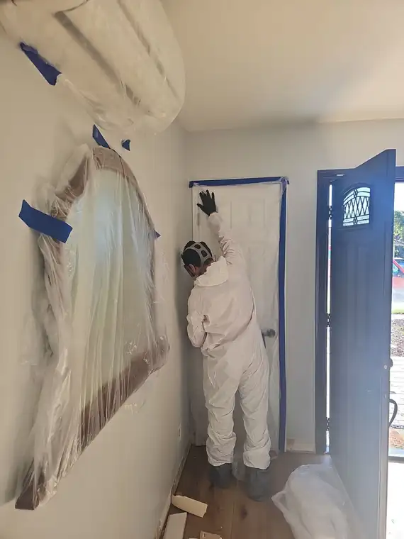 Plastic containment with a zipper door sealing a work area under negative air pressure