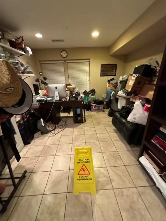 Bilingual caution wet floor sign, English and Spanish, on a tile floor during a water loss