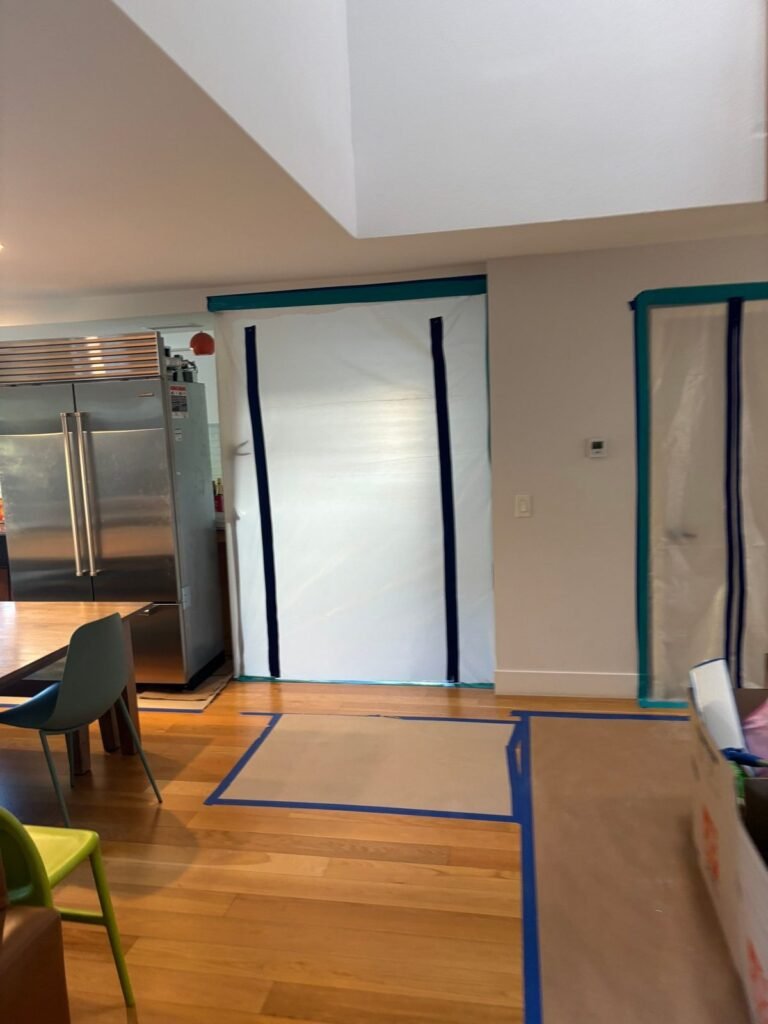A zippered containment barrier closing the passage beside a stainless refrigerator
