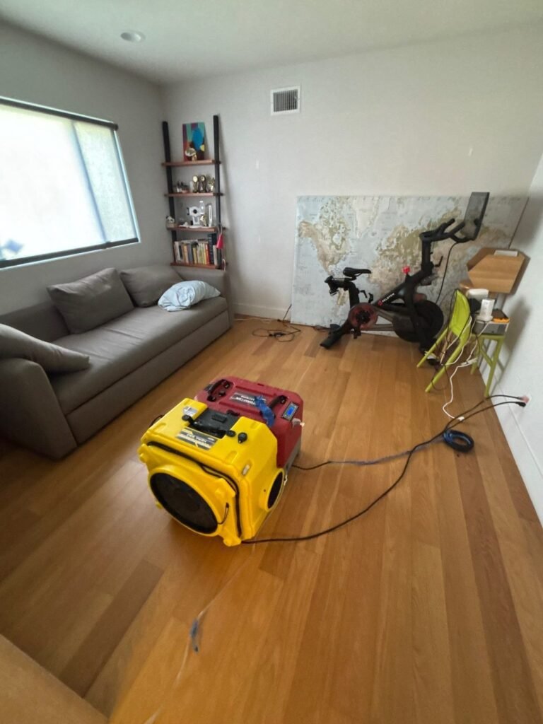 A yellow air mover running on hardwood in a furnished living room
